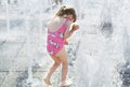 A happy little girl playing inside the city fountain on a hot summer day. Royalty Free Stock Photo