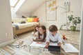 Happy little girl playing with mother and having fun while lying on the floor in living room at home, teenage boy using Royalty Free Stock Photo