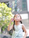 Happy little girl playing soap bubbles in garden