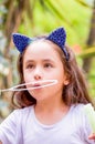 Happy little girl playing with soap bubbles on a summer nature, wearing a blue ears tiger accessories over her head in a Royalty Free Stock Photo