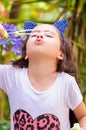 Happy little girl playing with soap bubbles on a summer nature, wearing a blue ears tiger accessories over her head in a Royalty Free Stock Photo