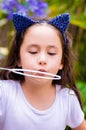 Happy little girl playing with soap bubbles on a summer nature, wearing a blue ears tiger accessories over her head in a Royalty Free Stock Photo