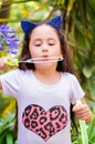 Happy little girl playing with soap bubbles on a summer nature, wearing a blue ears tiger accessories over her head in a Royalty Free Stock Photo