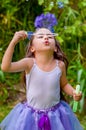 Happy little girl playing with soap bubbles on a summer nature, wearing a blue ears tiger accessories over her head and Royalty Free Stock Photo
