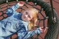 Happy little girl playing on a swing and having fun at kids modern playground Royalty Free Stock Photo