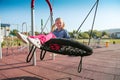 Happy little girl playing on a swing and having fun at kids modern playground Royalty Free Stock Photo