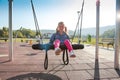 Happy little girl playing on a swing and having fun at kids modern playground Royalty Free Stock Photo