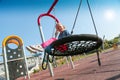 Happy little girl playing on a swing and having fun at kids modern playground Royalty Free Stock Photo