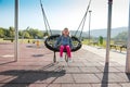 Happy little girl playing on a swing and having fun at kids modern playground Royalty Free Stock Photo