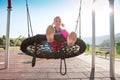 Happy little girl playing on a swing and having fun at kids modern playground Royalty Free Stock Photo