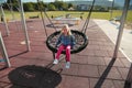 Happy little girl playing on a swing and having fun at kids modern playground Royalty Free Stock Photo