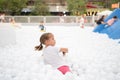 Happy little girl playing white plastic balls pool in amusement park. playground for kids Royalty Free Stock Photo