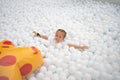 Happy little girl playing white plastic balls pool in amusement park. playground for kids Royalty Free Stock Photo