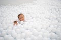 Happy little girl playing white plastic balls pool in amusement park. playground for kids Royalty Free Stock Photo