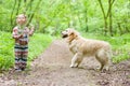 little girl plays with a dog standing on the forest road. Cute little girl with a dog, smiling. Child with dogs, pets Royalty Free Stock Photo