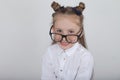 Happy little girl portrait, wearing white blouse and black frame eyeglasses, standing against white wooden background. Back to sch Royalty Free Stock Photo