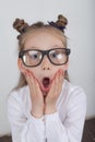 Happy little girl portrait, wearing white blouse and black frame eyeglasses, standing against white wooden background. Back to sch Royalty Free Stock Photo