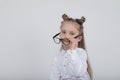 Happy little girl portrait, wearing white blouse and black frame eyeglasses, standing against white wooden background. Back to sch Royalty Free Stock Photo