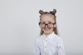 Happy little girl portrait, wearing white blouse and black frame eyeglasses, standing against white wooden background. Back to sch Royalty Free Stock Photo