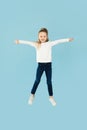 Happy Little Girl Posing In Mid Air Jumping, Blue Background Royalty Free Stock Photo