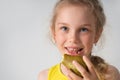 Happy little girl preschooler eating ripe juicy pear with great pleasure. Close up studio portrait isolated on white Royalty Free Stock Photo