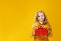 Happy little girl preschooler in a winter jacket is holding a box with a gift. The concept of giving and receiving gifts. Royalty Free Stock Photo