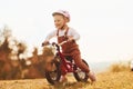 Happy little girl in protective hat riding her bike outdoors at sunny day near forest Royalty Free Stock Photo