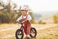 Happy little girl in protective hat riding her bike outdoors at sunny day near forest Royalty Free Stock Photo