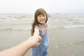 Happy little girl pull parent`s hand to the sea with big smile and waves on background Royalty Free Stock Photo