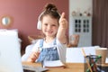Happy little girl pupil study online using laptop at home, smiling small child show thumb up recommend class or lesson. Royalty Free Stock Photo