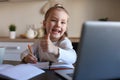 Happy little girl pupil study online using laptop at home, smiling small child show thumb up recommend class or lesson Royalty Free Stock Photo