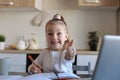 Happy little girl pupil study online using laptop at home, smiling small child show thumb up recommend class or lesson Royalty Free Stock Photo