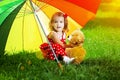 Happy little girl with a rainbow umbrella in park. Child playing Royalty Free Stock Photo