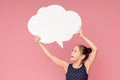 Happy little girl with raised hands holding speech bubble and looking at camera