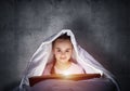 Happy little girl reading book in bed