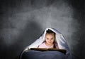 Happy little girl reading book in bed