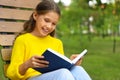 Happy little girl reading book in park Royalty Free Stock Photo