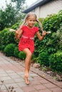 happy little girl in red dress with pigtails jumping in the garden. Summer holidays. Royalty Free Stock Photo