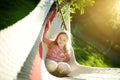 Happy little girl relaxing in hammock on beautiful summer day. Cute child having fun in spring garden. Royalty Free Stock Photo
