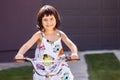 Happy little girl riding bike on alley while looking at camera and smiling Royalty Free Stock Photo