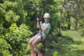 Happy little girl riding a zip line in a lush tropical forest