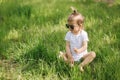 Happy little girl sits on the grass outdoors. Cute baby girl in white bodysuit and sunglasses on the backyard. Adorable Royalty Free Stock Photo