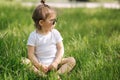 Happy little girl sits on the grass outdoors. Cute baby girl in white bodysuit and sunglasses on the backyard. Adorable Royalty Free Stock Photo