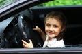 Happy little girl sitting behind the wheel of dad`s car Royalty Free Stock Photo