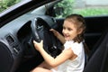 Happy little girl sitting behind the wheel of dad`s car Royalty Free Stock Photo