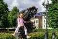 Happy little girl sitting on bronze sculpture of clown