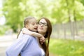 Happy little girl sitting on her mom shoulders or back on a sunny summer day and kissing her mother cheek Royalty Free Stock Photo