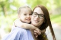 Happy little girl sitting on her mom shoulders or back on a sunny summer day and kissing her mother cheek Royalty Free Stock Photo