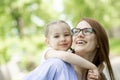 Happy little girl sitting on her mom shoulders or back on a sunny summer day and kissing her mother cheek Royalty Free Stock Photo