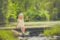 Happy little girl sitting on wooden bridge Royalty Free Stock Photo